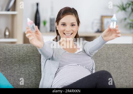 allegra donna incinta che tiene biberon Foto Stock