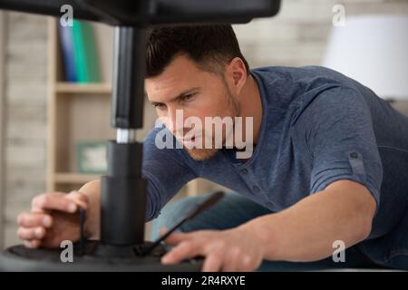 l'uomo concentrato sta assemblando nuovi mobili Foto Stock