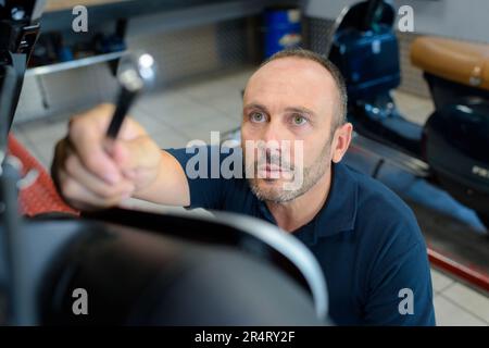 meccanico che raggiunge l'attrezzo Foto Stock