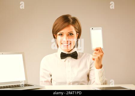 Immagine in stile vintage di una donna che presenta internet e dispositivi digitali con ampio COPYSPACE. Indossando una camicia bianca e una cravatta, mostra uno smar Foto Stock