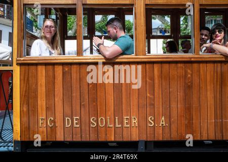 Turisti all'interno del tram d'epoca al centro del villaggio di Soller. Il tram opera un servizio 5kms dalla stazione ferroviaria nel villaggio di Soller al Foto Stock