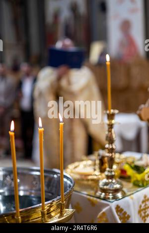 particolare delle candele con il parroco ortodosso che celebra la messa Foto Stock