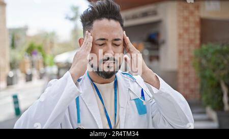 Un giovane medico latino ha sottolineato sulla terrazza della caffetteria Foto Stock