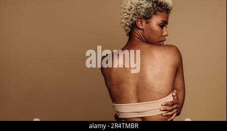 Vista posteriore di una giovane donna in piedi con sicurezza in uno scatto da studio con la schiena alla telecamera. Donna che esprime positività corporea e fiducia in se stessi thro Foto Stock