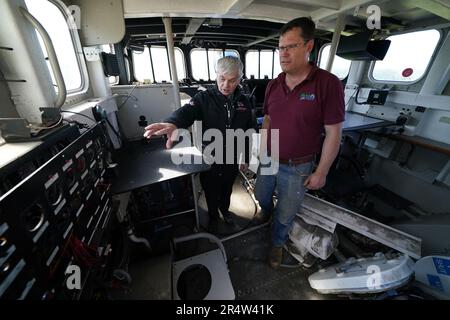 Martyn Steedman insieme a David Buchan dalla RNLI nella timoneria a bordo dell'ex scialuppa di salvataggio RNLI dopo essere stato abbassato nel suo campeggio presso la Mains Farm a Thornhill, Stirlingshire, dove la nave Tyne Class da 26 tonnellate sarà trasformata in un baccello glamping. Data immagine: Martedì 30 maggio 2023. Foto Stock