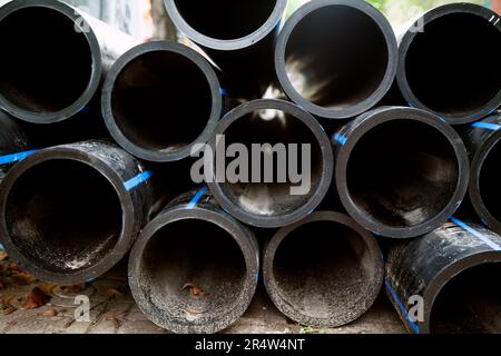 Pila di tubi in HDPE neri preparati per il trasporto dell'acqua. Molti tubi di irrigazione in plastica in polietilene ad alta densità Foto Stock