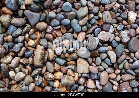 Pietra schiacciata sulla riva del mare. Messa a fuoco selettiva sull'oggetto. Le pietre sono state posate a terra nel giardino come sfondo. Sfocatura dello sfondo. Pebble st Foto Stock