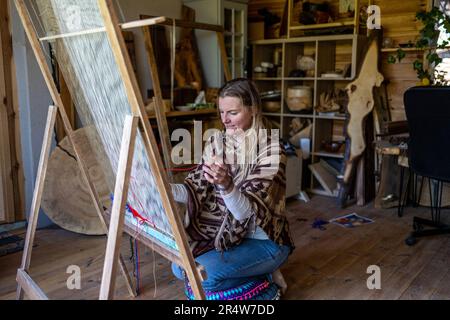 Donna mrafty tessendo ad un telaio al suo laboratorio Foto Stock