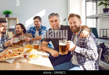 Amici maschi felici bevendo birra a casa insieme Foto Stock