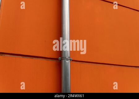 gronde o downspout, casa particolare della facciata su un edificio con intonaco arancione. tubi di scarico dell'acqua in acciaio inox Foto Stock