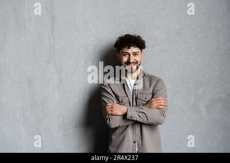 Felice sicuro bello uomo a casa ritratto casa tua sicuro. Giovane padrone di casa maschile posa in appartamento con sfondo bianco interno, tenendo la mano Foto Stock