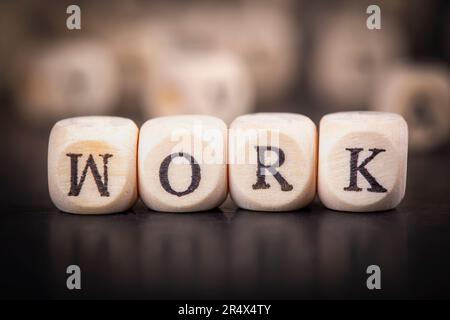 Parola di lavoro fatta con i blocchi di costruzione. Lavori su cubetti di legno su blocco note grigio. Concetto aziendale. Foto Stock