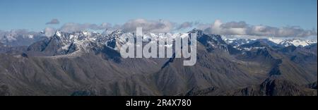 Panoramica delle cime grigie e innevate della catena montuosa Chugach contro un cielo blu, percorsa lungo il Williwaw Lakes Trail nel Chugac... Foto Stock