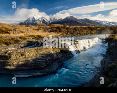 Vista panoramica della Cascada Rio Paine con le vette del Cuernos del Paine in lontananza; Parco Nazionale Torres del Paine, Patagonia, Cile Foto Stock