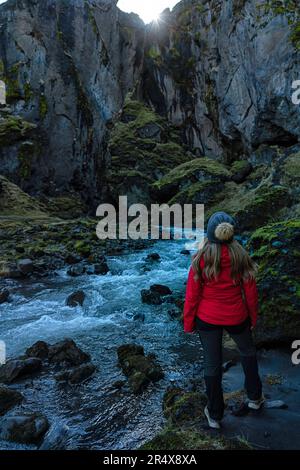 Vista da dietro di una donna che esplora i canyon e il paesaggio di Thorsmork, un'area di eccezionale bellezza nel sud dell'Islanda Foto Stock