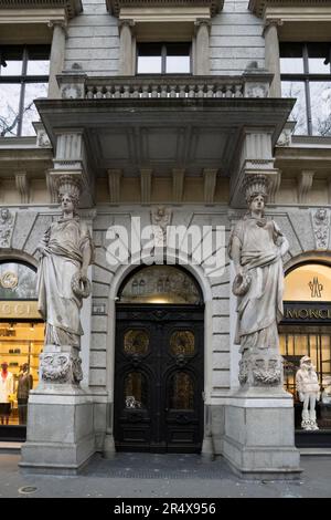 Budapest, Ungheria - 28th novembre 2022: Due statue e una porta in metallo ornato in un edificio decorato ingresso in una strada Budapest, Ungheria. Foto Stock