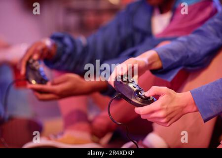 Primo piano dei giovani che giocano a videogame retrò in stile neon light 80s, spazio copia Foto Stock