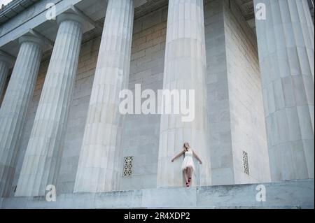 Adolescente in piedi contro una grande colonna al Lincoln Memorial di Washington DC, USA; Washington, District of Columbia, Stati Uniti d'America Foto Stock