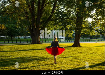 La ragazza adolescente si staglia con la luce del sole che splende attraverso una gonna rossa sul terreno del Campidoglio degli Stati Uniti Foto Stock