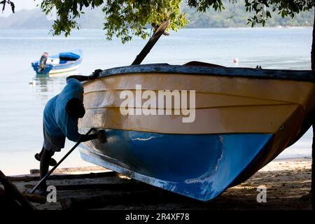 Il pescatore di Bluefields Bay pulisce la sua barca in Giamaica; Bluefields Bay, Giamaica Foto Stock