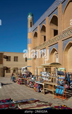 Beni in vendita e Madrasa di Islam Khoja a Itchan Kala, sito patrimonio dell'umanità dell'UNESCO, a Khiva, Uzbekistan; Khiva, Uzbekistan Foto Stock