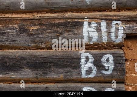 L'iscrizione sul vecchio muro di tronchi. Vecchia casa di legno di tronchi. Scritte in vernice bianca. Foto Stock