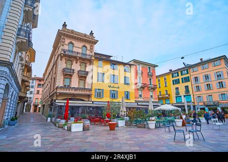 LUGANO, SVIZZERA - 13 MARZO 2022: Case colorate di Piazza Riforma con ristoranti all'aperto, bar e negozi turistici, il 13 marzo a Lugano Foto Stock