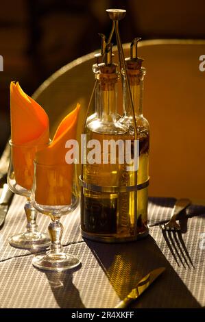 Olio d'oliva e bicchieri da vino su un tavolo al sole; Nizza, Costa Azzurra, Francia Foto Stock