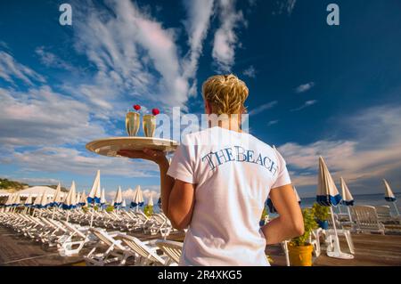 Server con vassoio di cocktail sulla spiaggia di Nizza, Francia; Nizza, Costa Azzurra, Francia Foto Stock