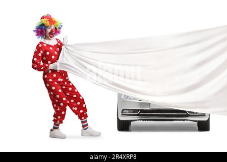 Clown tirando un grande panno bianco di fronte a una nuova auto isolato su sfondo bianco Foto Stock