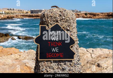 Diventiamo o pensiamo simbolo. Parola di concetto che cosa pensiamo che diventiamo sulla bella lavagna nera. Bellissimo sfondo mare in pietra. Azienda che diventiamo o t Foto Stock