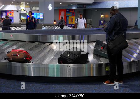 Le persone in attesa di ritirare i bagagli da un nastro trasportatore all'aeroporto LaGuardia, nell'area ritiro bagagli del Terminal B, New York City. Foto Stock