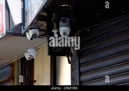 Un gruppo di telecamere di sorveglianza a circuito chiuso e di sicurezza CCTV all'esterno di un negozio puntato in più direzioni verso una strada pubblica. Foto Stock