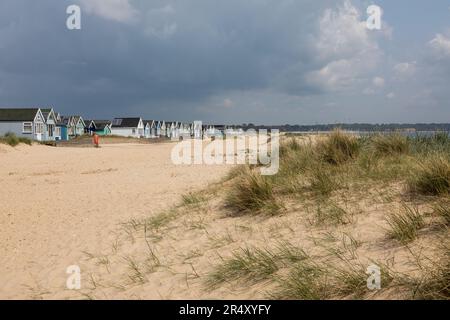 Cielo tempestoso e colorate capanne in legno dipinte a Hengistbury Head, vicino a Mudeford, Christchurch, Dorset. Inghilterra, Regno Unito Foto Stock