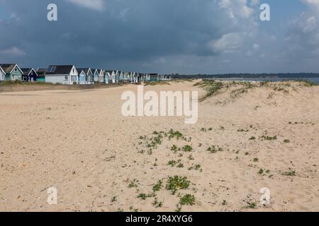 Cielo tempestoso e colorate capanne in legno dipinte a Hengistbury Head, vicino a Mudeford, Christchurch, Dorset. Inghilterra, Regno Unito Foto Stock