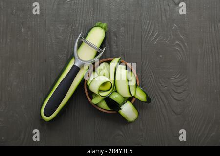 Ciotola con fette di zucchine fresche su fondo di legno nero Foto Stock