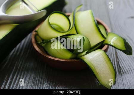 Ciotola con fette di zucchine fresche su fondo di legno nero Foto Stock