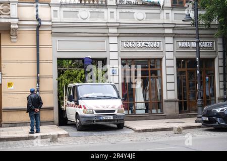 Pulmino con un albero carico in cima schiacciato sotto il soffitto basso dell'entrata del vicolo, che arriva alla strada. Tbilisi Georgia Foto Stock