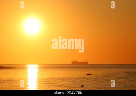 Tramonto sull'estuario del fiume Wyre e sulla baia di Morecambe da Knott End-on-Sea con mare di vongola e silhouette di grande barca all'orizzonte in una soleggiata serata di maggio. Foto Stock