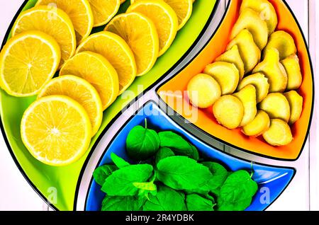 Concetto con frutta fresca, verdura e spezie verdi. Foglie di limone, zenzero e menta in ciotole colorate. Foto Stock