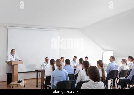 Dottore senior che tiene lezioni in sala conferenze con schermo di proiezione Foto Stock