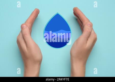 Donna con goccia d'acqua di carta su sfondo azzurro, vista dall'alto Foto Stock