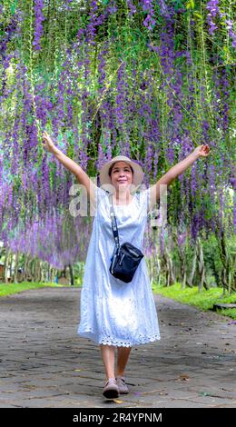 Una donna delicata e gentile in un bellissimo giardino wisteria cinese a Giang Dien cascata zona turistica, Dong Nai provincia, Vietnam Foto Stock