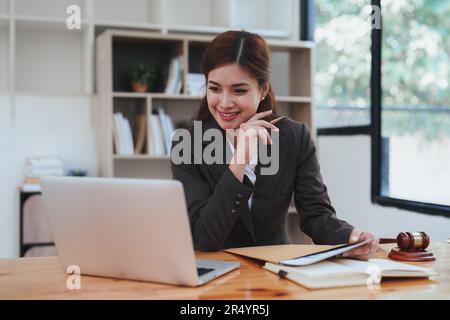 Giovane avvocato in ufficio donna d'affari e avvocati che discutono di carte contrattuali con scala in ottone su scrivania in legno in ufficio. Diritto, servizi legali, consulenza Foto Stock