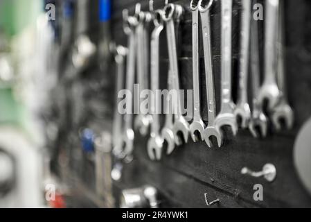 Chiavi e altri accessori appesi su una tavola portautensili in un negozio di riparazione di biciclette. Vista ravvicinata con messa a fuoco selettiva. Foto Stock