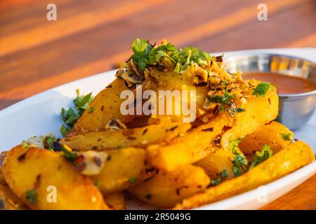 Un piatto di spicchi di patate fritte con erbe speziate Foto Stock