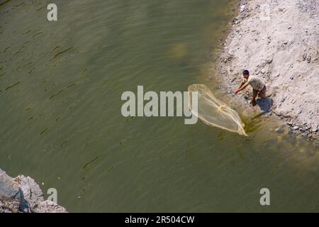 Pesca tradizionale pescatore gettando la rete sul fiume per catturare i pesci in Nepal Foto Stock