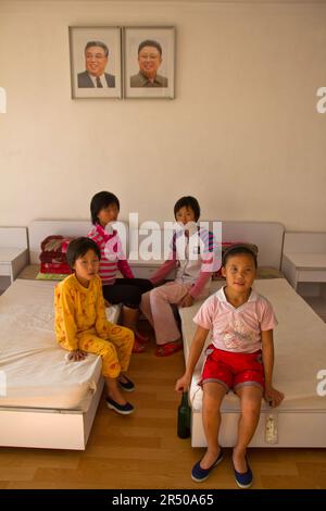 orfani nordcoreani in un orfanotrofio di fronte alle immagini dei leader della corea del nord Foto Stock
