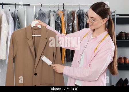 Giovane donna che usa un rullo per pelucchi adesivo a secco Foto Stock