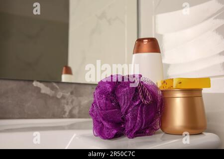 Soffio doccia viola e prodotti cosmetici sul lavandino in bagno, spazio per il testo Foto Stock